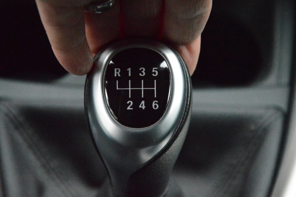 Detailed close-up of a hand operating a manual car transmission gear lever in a car interior.