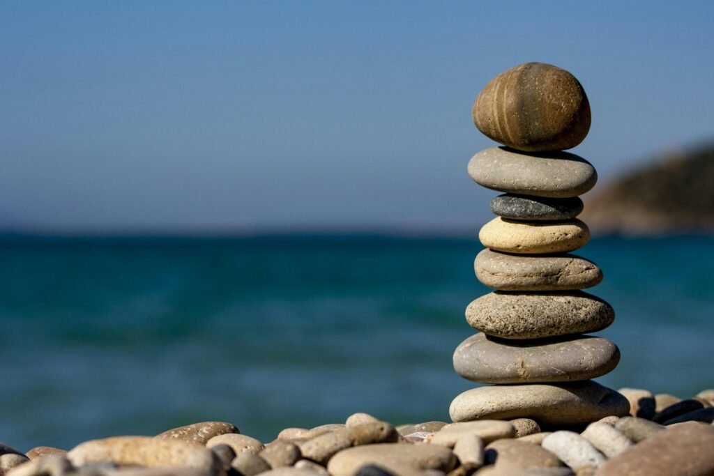 A stack of balanced stones on a beach with a tranquil ocean backdrop for meditation and zen.