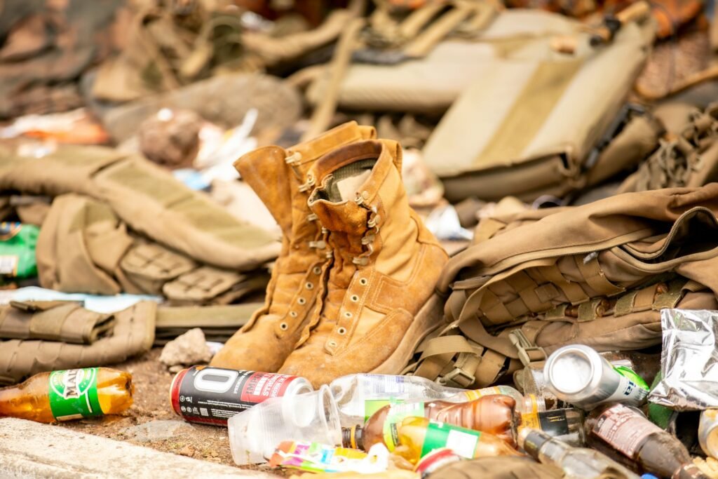 A close-up of abandoned military gear and litter on the ground.