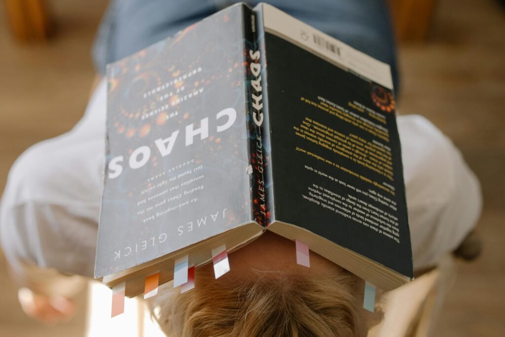 Person resting with an open book on their face, embracing leisure reading.