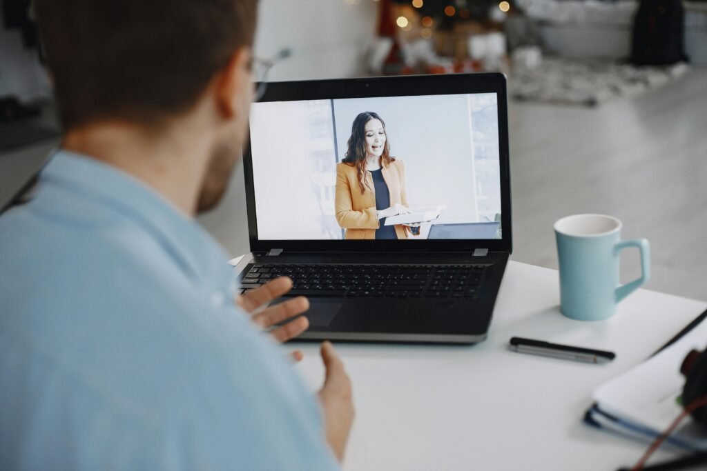 A man participating in a video conference call with a colleague on a laptop at home.