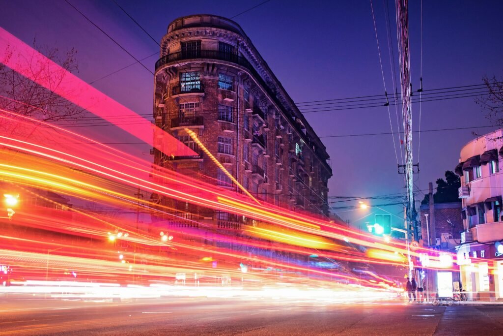 A dynamic long exposure of traffic light streaks against historic Shanghai architecture at night.